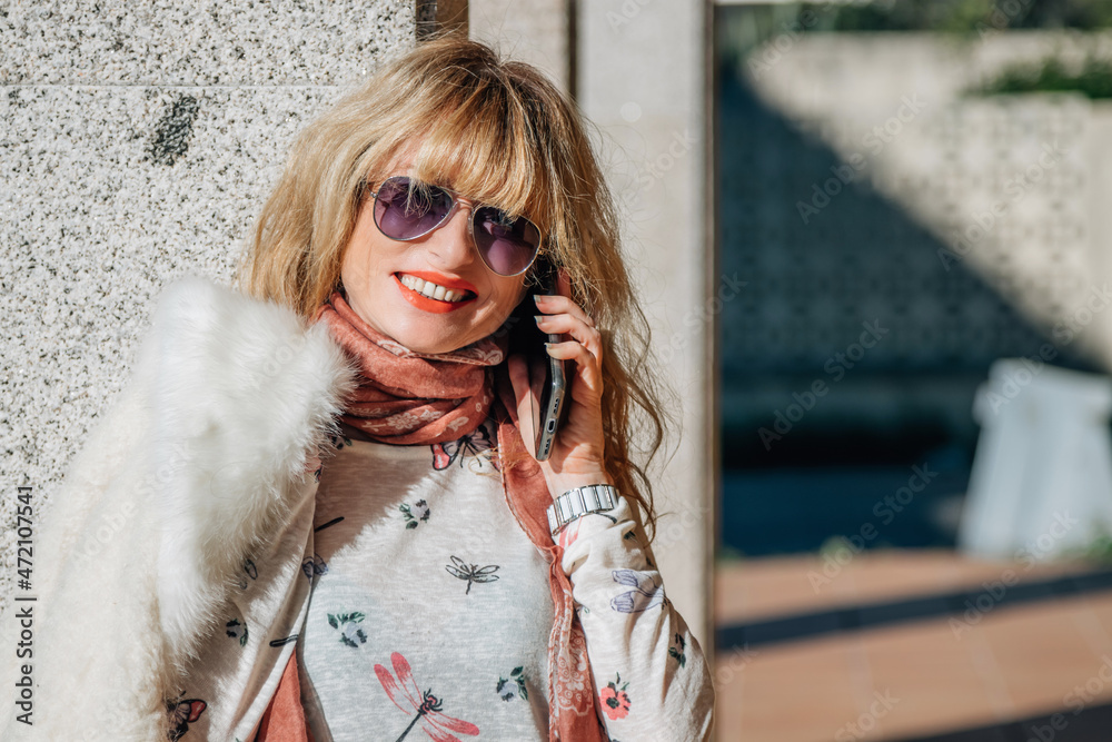 adult woman talking on mobile phone in the street wearing sunglasses adult woman talking on mobile phone in the street wearing sunglasses