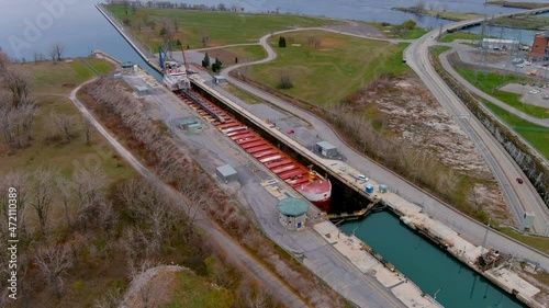 A self discharging bulk carrier ship prepares to cross the locks of the Beauharnois Canal in the St Lawrence Seaway, near Montreal, Quebec. High quality 4K aerial view. photo