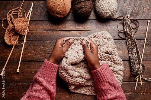 Canvas-taulu Top view close up of female hands knitting against dark wooden background, copy