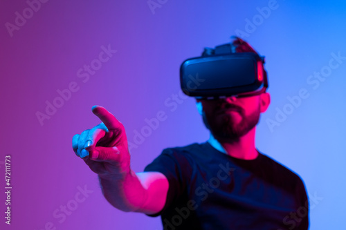 Amazed young bearded man, wearing high tech smart vr goggles, watching 360 degree video or playing a video game in metaverse.