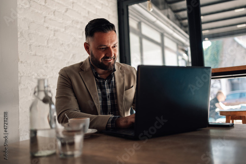 Businessman working on his laptop while drinking coffee in a cafe