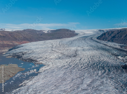Panoramic photo of icelandic glacier at Hoffell taken on a sunny day. Visible glacier, tongue, chunks of ice in the water.