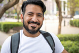 portrait of latin man with beard smiling at camera backpack