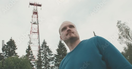4G and 5G cellular radio tower. There is a man standing nearby. Nature, outdoors
