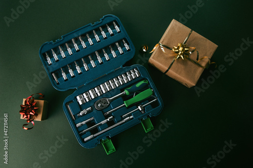 Tools kit in a green case, toolbox on a green background with Christmas gifts. 