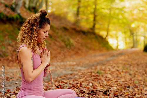 young woman practicing yoga and meditating sitting in a forest.