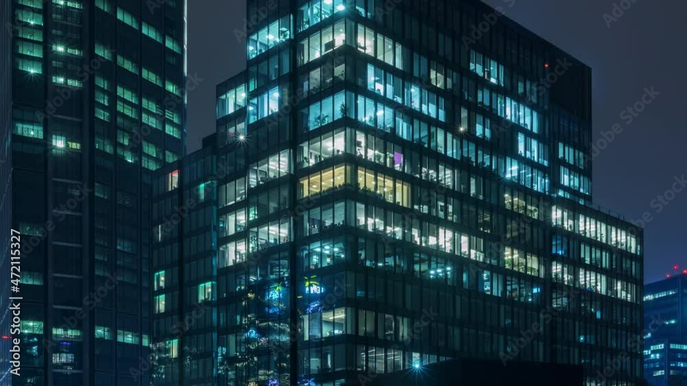 Time lapse day to night transition blinking office windows lights in business center building downtown. Corporate business, high skyscraper glass surface. Light in building windows turn on and off Time lapse day to night transition blinking office windows lights in business center building downtown. Corporate business, high skyscraper glass surface. Light in building windows turn on and off