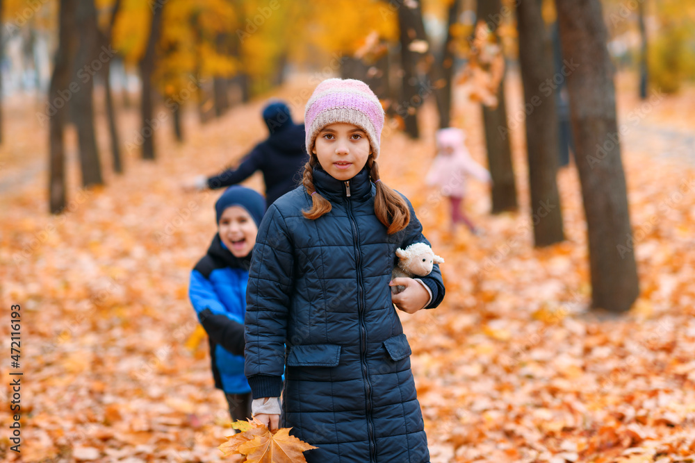 Children playing with yellow maple leaves in autumn city park. Fall season, beautiful nature.