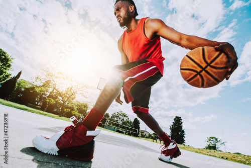 Basketball street player dribbling with ball on the court - Streetball, training and activity concept