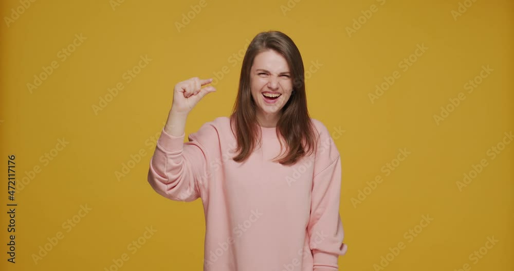 Joyful laughing young girl showing little bit gesture tiny size by finger. Small prices or rates and sale concept