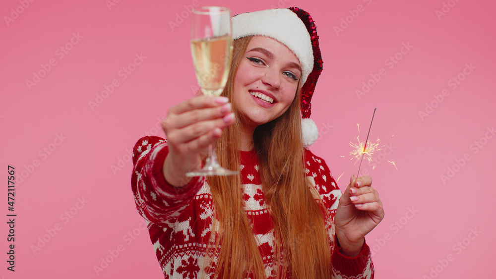 Joyful Christmas Santa adult cute girl dancing with bengal sparklers fireworks and champagne glass, sending wishes and congratulation on red background. Happy New Year celebration merry holiday