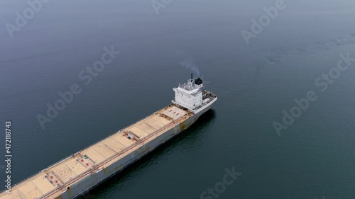 A bulk carrier ship navigates the St Lawrence Seaway as it approaches the Beauharnois Canal near Montreal, Quebec. High quality 4K aerial view. photo