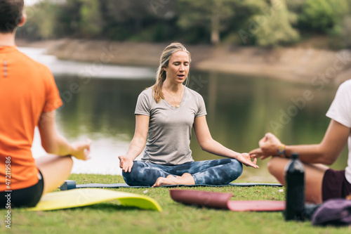 Instructor doing the lotus pose during a yoga class in a park