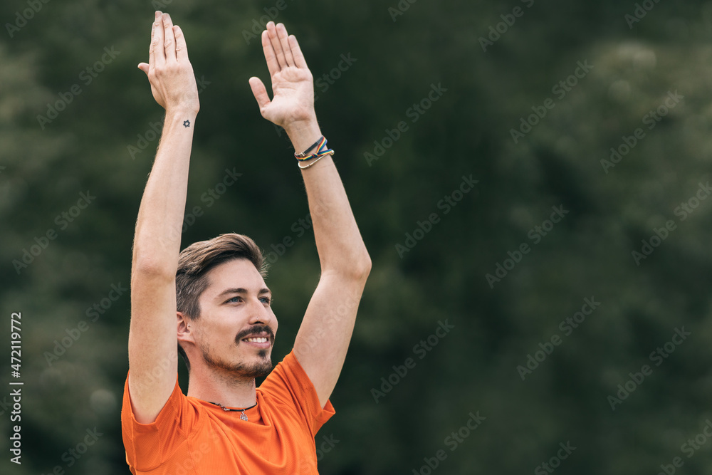 Man with happy expression doing yoga outdoors