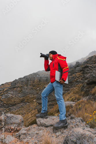 travel photographer with camera and laptop in the mountains