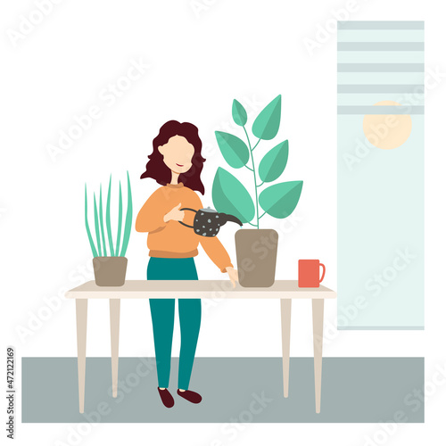 A girl is standing at her desk in the office and watering the plants.