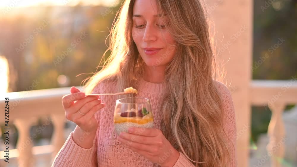 Woman eating a fruit salad with chia seeds in a park at the sunset