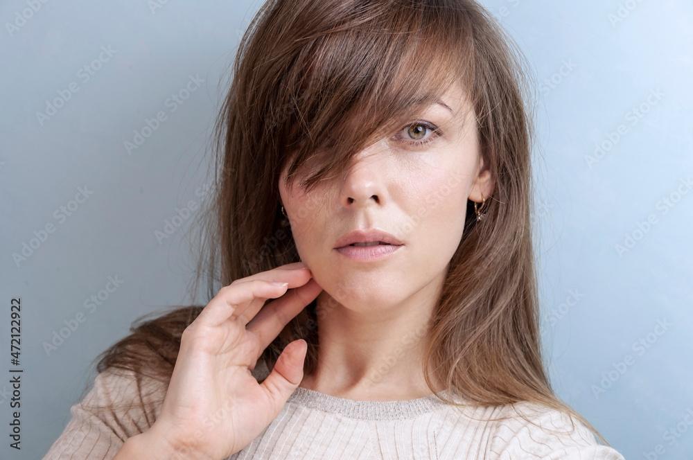 Close-up portrait of beautiful brunette woman on blue gray background Close-up portrait of beautiful brunette woman on blue gray background