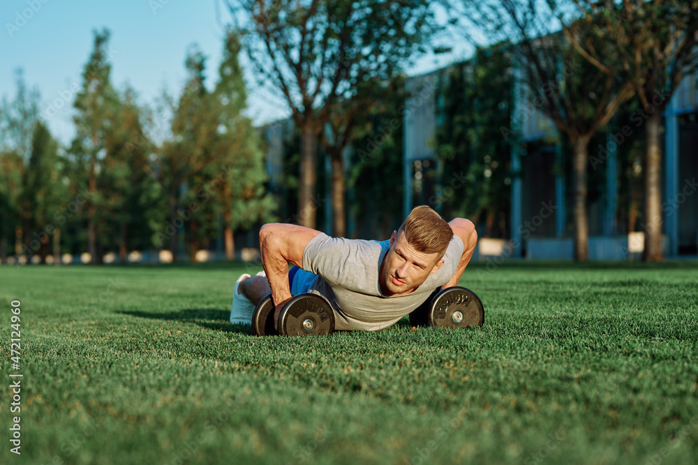 Fototapeta premium athletic man training with dumbbells in the morning Park