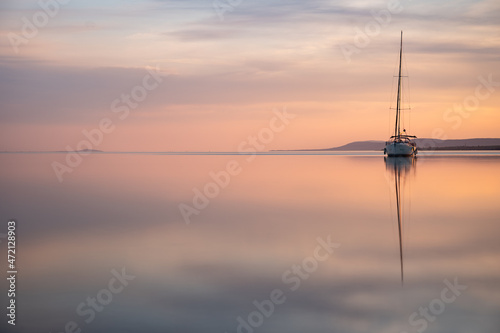 a sailing boat at sunset on a calm lake photo