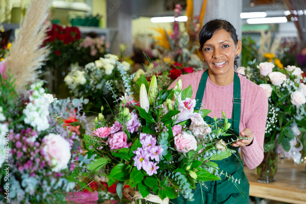 Florist in an apron creates bouquets in a flower shop