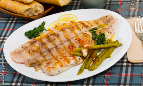 Appetizing baked ocean perch fillet with baked asparagus, sliced lemon and greens ..