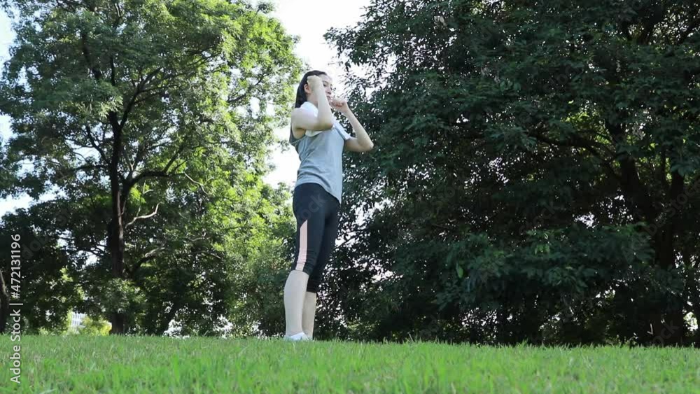 Asian woman exercising in a beautiful scenery park in the morning : Young woman with a healthy lifestyle, she spreads her arms to hold her body and looks the other way. warm up outdoors Asian woman exercising in a beautiful scenery park in the morning : Young woman with a healthy lifestyle, she spreads her arms to hold her body and looks the other way. warm up outdoors