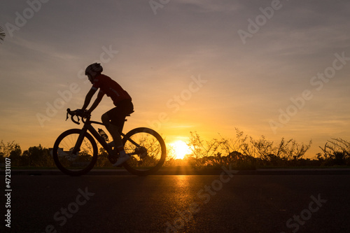 Fototapeta Naklejka Na Ścianę i Meble -  a man ride a bicycle at sunset with sunbeam over silhouette trees background