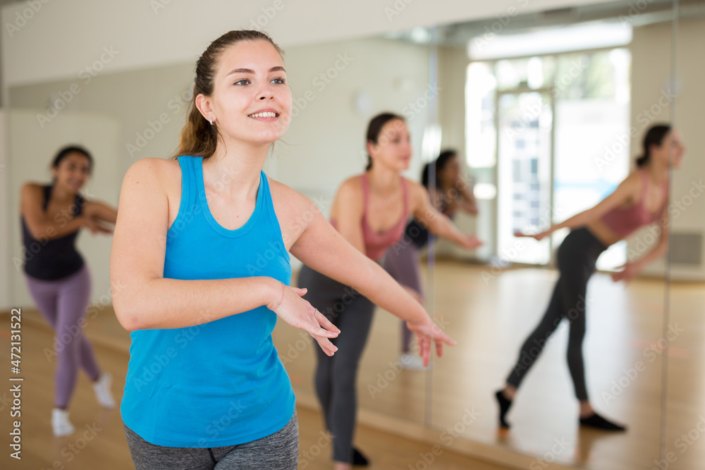 Fototapeta premium Young adult athletic woman dancing during group class in dance center