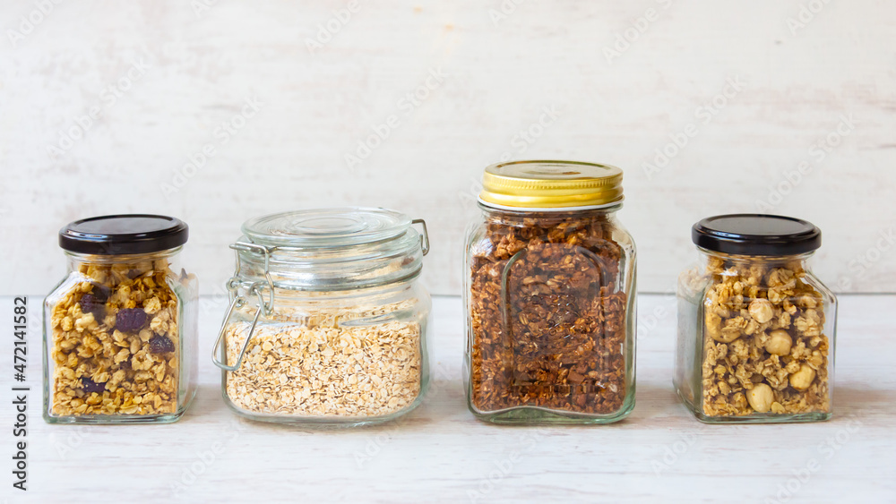 Jars full of oats and various crunchy granola - plain, dried fruits, nuts and chocolate. Healthy eating concept.
