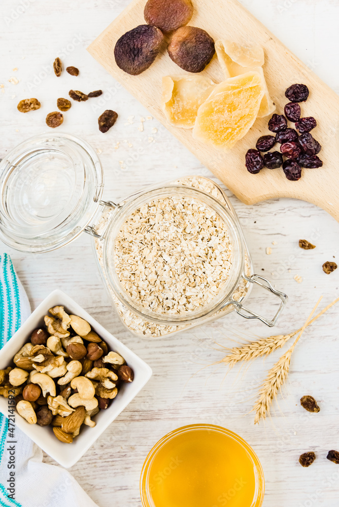Top view of raw ingredients for homemade granola preparation - oats, nuts, honey and dried fruits. Healthy eating.