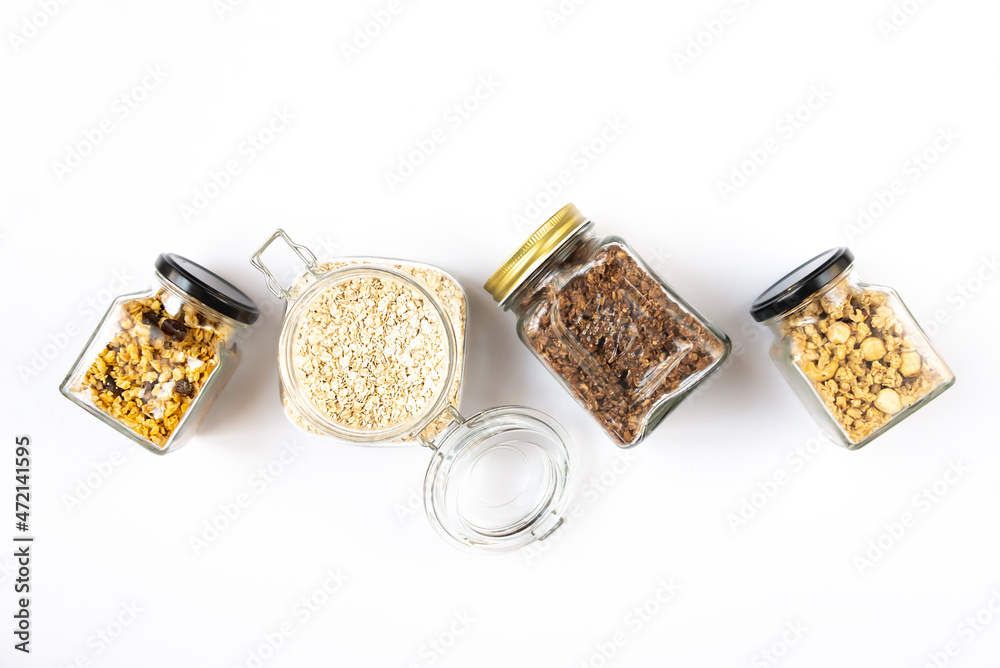 Top view of jars full of oats and various crunchy granola - plain, dried fruits, nuts and chocolate. Healthy eating concept.