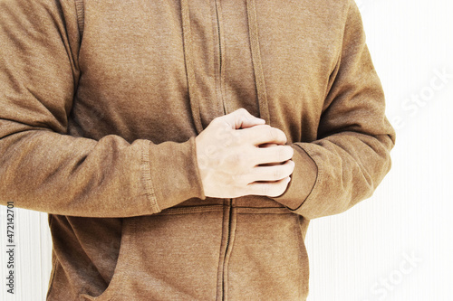 Hombre latino vestido con una chaqueta de tela color Café, mostrando las manos, sobre un fondo blanco.