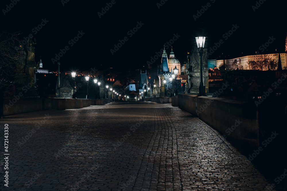 Street light lamp and paving sidewalk on the empty Charles Bridge on the Vltava River at night in the center of Prague
