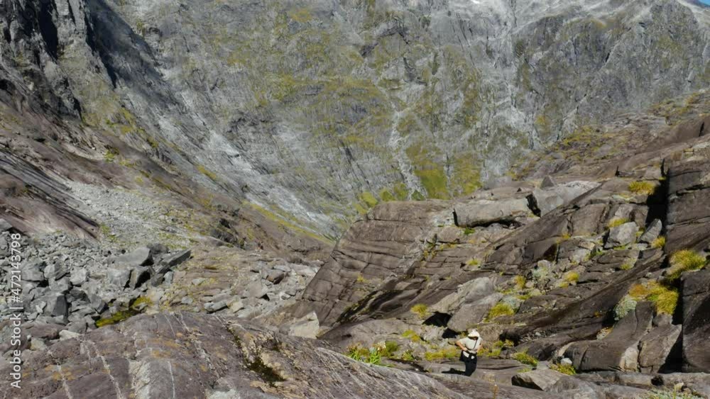 Aerial top down shot of exhausted hiker climbing and hiking up steep rocky mountains during sunlight - Gertrude Saddle Walk,NZ