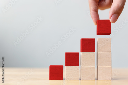 Photography Hand holding red wood block on top step