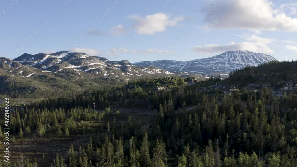 Slow push out with mountain cabins in front of snow covered mountain range drone 4K Slow push out with mountain cabins in front of snow covered mountain range drone 4K