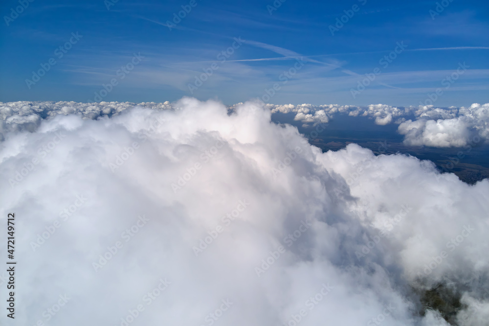 Aerial view from airplane window at high altitude of earth covered with puffy cumulus clouds forming before rainstorm