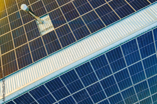 Aerial view of surface of blue photovoltaic solar panels mounted on building roof for producing clean ecological electricity. Production of renewable energy concept