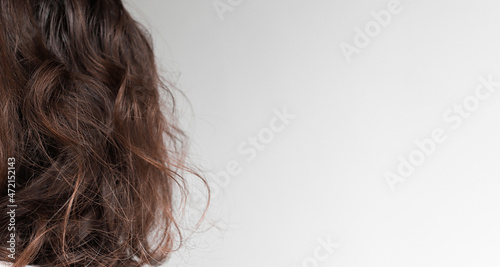 Curly, beautiful hair of a brunette woman, back view. Banner with copy space and gray background, mockup for design.