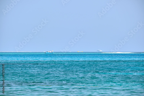 Seascape with ripple surface of blue sea water with distant ships floating on calm waves