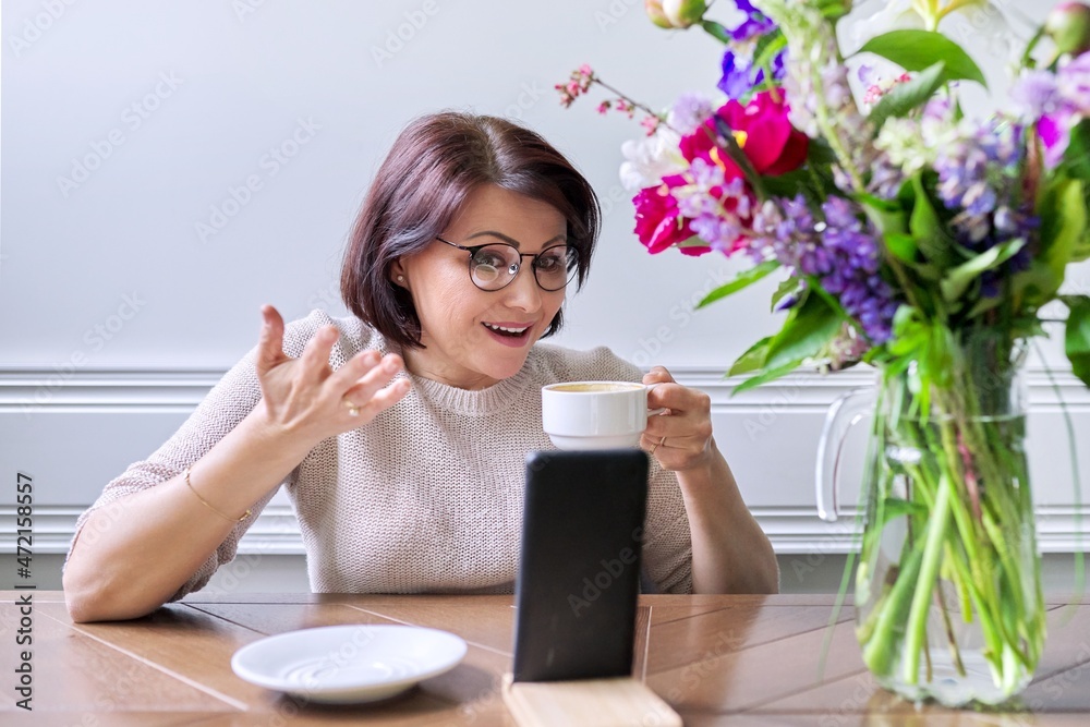 Middle-aged woman sitting at home using smartphone for video call Middle-aged woman sitting at home using smartphone for video call