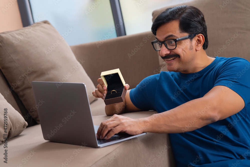 Happy man showing ring over video conference Happy man showing ring over video conference