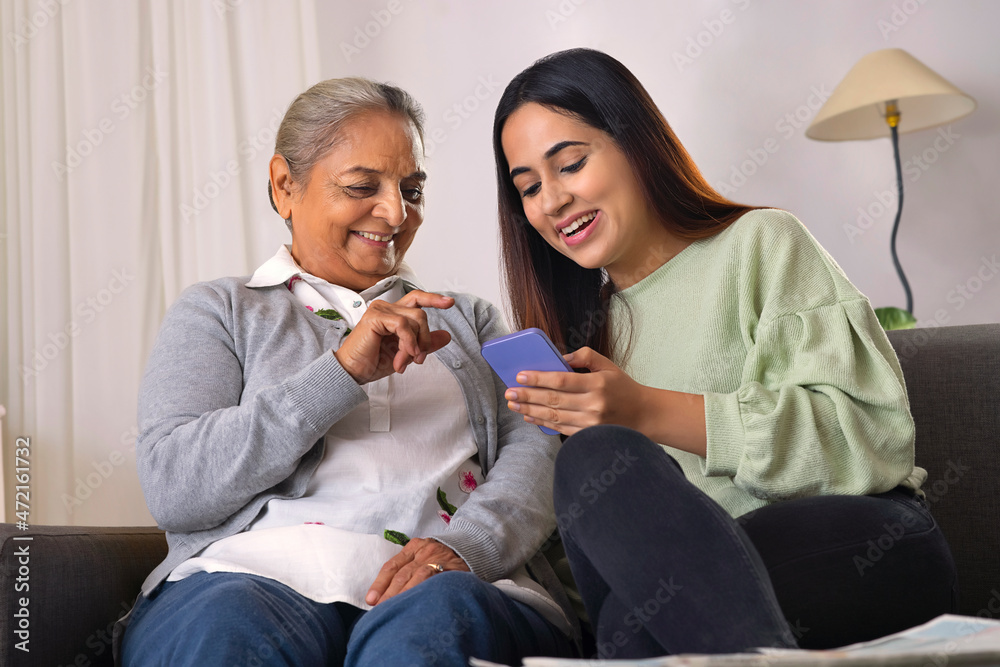 Grandmother and granddaughter using smartphone together at home