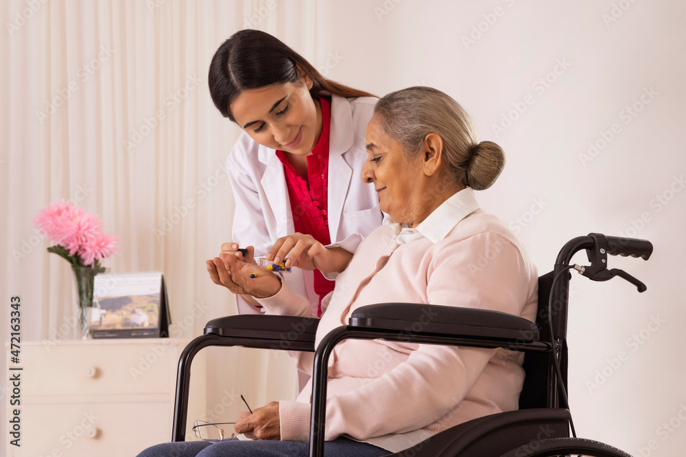 Fototapeta premium Nurse giving medicine to an old woman sitting on wheel chair