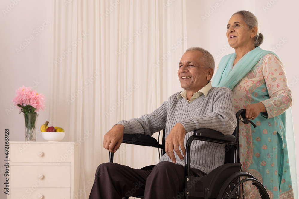Senior woman moving her husband sitting on wheel chair Senior woman moving her husband sitting on wheel chair