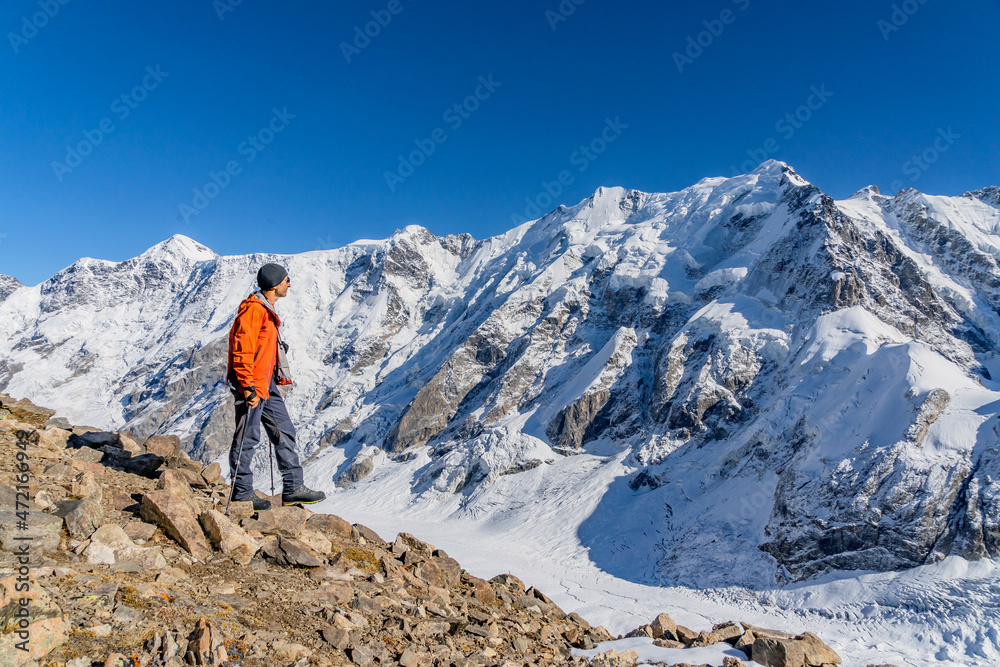 Beautiful landscape with mountains, blue huge glacier and a middle-aged mountaineer man against the background of mountains, glacier