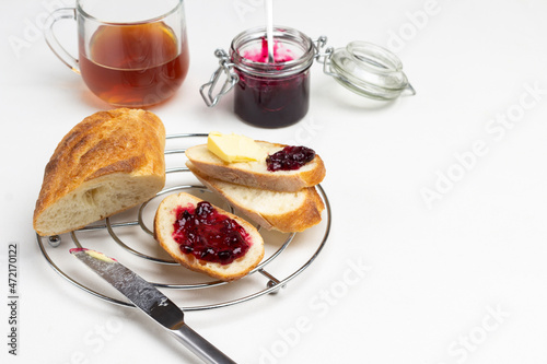 Knife, Loaf slices with butter and jam on metal stand.
