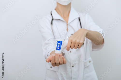 Fototapeta Naklejka Na Ścianę i Meble -  Temperature measurement gun in doctor hands. Close-up shot of doctor wearing protective surgical mask ready to use infrared isometric thermometer gun to check body temperature for virus symptoms.