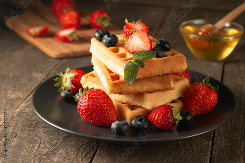 Fresh homemade food of berry Belgian waffles with honey  chocolate  strawberry  blueberry  maple syrup and cream. Healthy dessert breakfast concept with juice